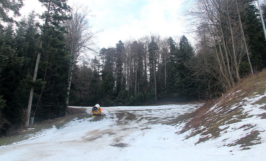 Smutné sněhové dělo a zbytky sněhu na vedlejší sjezdovce