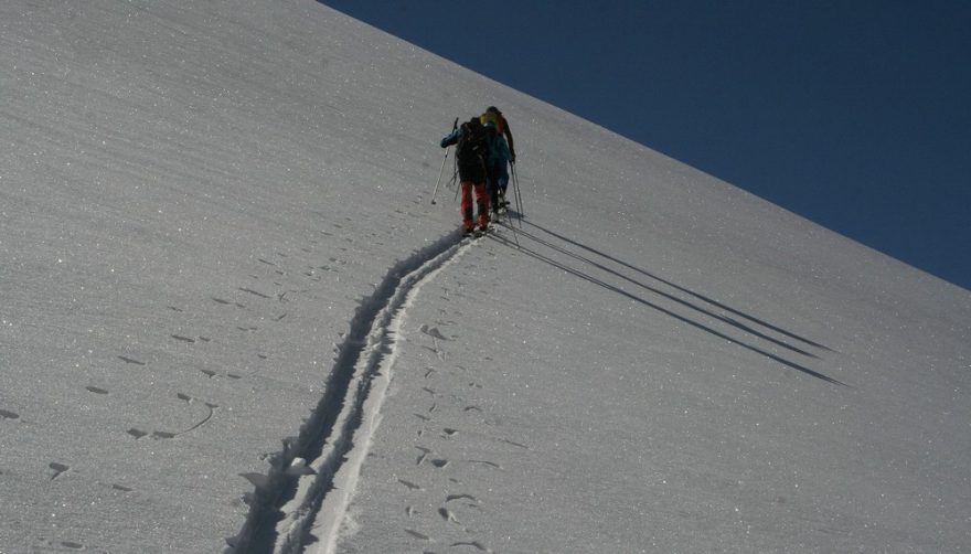 V řadě za sebou tři skialpinisti jdou